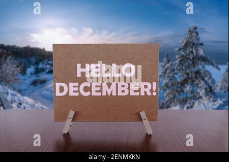 Hello December text on card on the table with sunny winter landscape background. Stock Photo