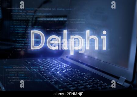 Delphi inscription against laptop and code background. Learn programming language, computer courses, training. Stock Photo