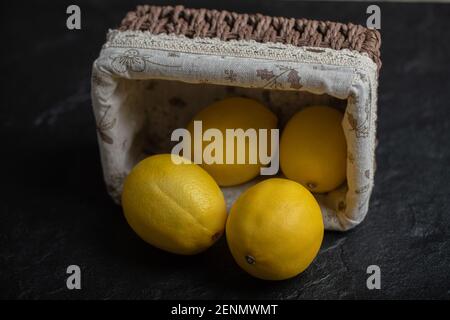 Basket full with fresh ripe lemons on black background Stock Photo