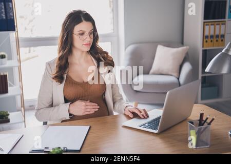 Photo portrait of pregnant lady working on laptop typing browsing in modern office Stock Photo