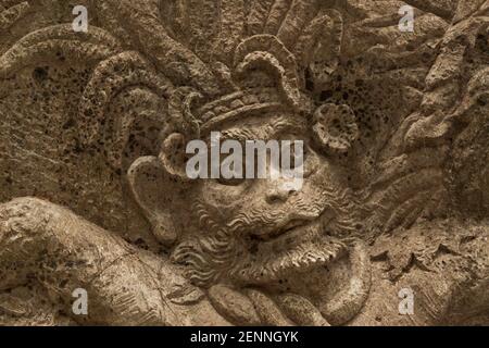 Close-up of the face of a Hindu god figure carved on a wall near Sacred Monkey Forest in Bali Stock Photo