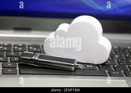 Cloud data storage technology, storing data in the cloud abstract. Cloud and a usb memory stick, pen drive laying on a laptop keyboard. Online private Stock Photo