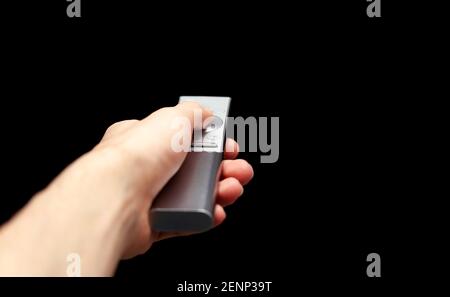 Hand holding a TV remote control, first person pov, man changing channels, isolated, cut out, blank black screen. Pressing a button on a modern televi Stock Photo