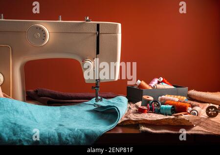 Sewing machine and sewing accessories on a brown background. The concept of sewing. Stock Photo