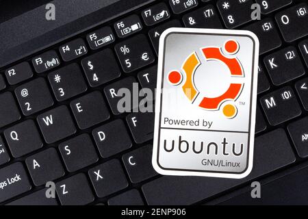 Powered by Ubuntu GNU Linux operating system sticker, logo symbol label closeup, laptop keyboard. Debian open source software technology concept, top Stock Photo