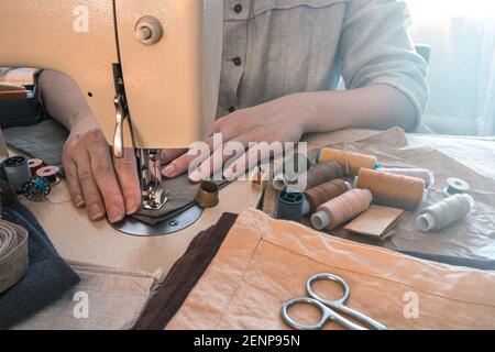 A woman tailor sews on a sewing machine. Side view. The concept of sewing. Stock Photo