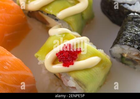 Sushi rolls with avocado and tobiko caviar and philadelphia rolls. Macro. Photo can be used as a whole background. Stock Photo