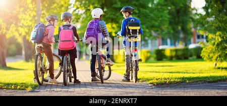 Children with rucksacks riding on bikes in the park near school Stock Photo