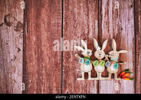 Wooden Easter bunnies with decoration and the text Easter written on eggs. Stock Photo