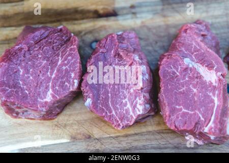 Top down view on three raw beef filet mignon steaks on wodden background. Stock Photo