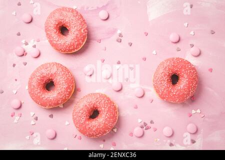 Donuts with pink icing and pink chocolate beans on pink background Stock Photo