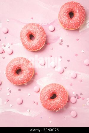 Donuts with pink icing and pink chocolate beans on pink background Stock Photo