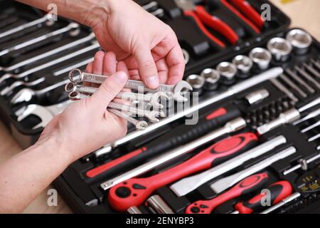 Tool store. Closeup of male hand holding wrenches. Auto repair kit in toolbox. Repairman instruments set. Inside the toolbox there are black-red wrenc Stock Photo