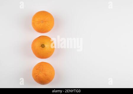 Three whole fresh oranges placed on white table Stock Photo