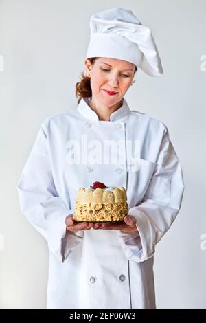 pastry chef is a woman in uniform. The pastry chef holds the cake