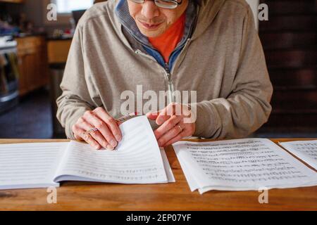 close-up of man transcribing music with pencil on paper at table Stock Photo