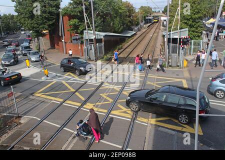 A railway level crossing with cars and pedestrians crossing the track.  Highams Park, London Stock Photo