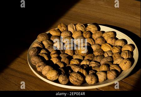 Plate of walnuts standing on a wooden table in a hard light Stock Photo