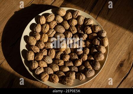 Plate of walnuts standing on a wooden table in a hard light Stock Photo