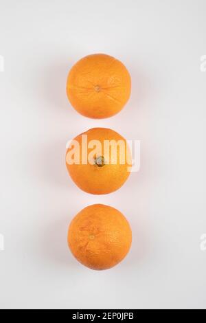 Three whole fresh oranges placed on white table Stock Photo