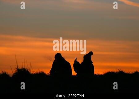 Huddersfield, UK. 26th Feb, 2021. Silhouette of a couple watching a spectacular sunset from Castle Hill in Huddersfield.After several weeks of heavy rain and snow, the UK is currently enjoying the first signs of spring. Credit: SOPA Images Limited/Alamy Live News Stock Photo