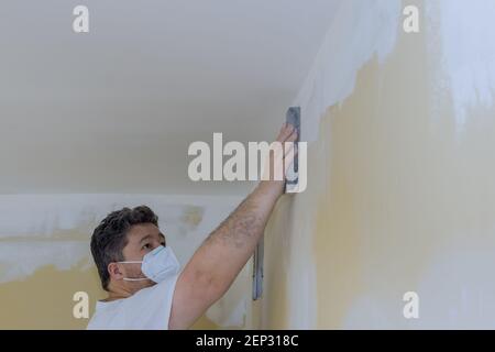 Contractor using sand trowel sanding the drywall on the wall Stock Photo