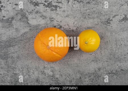 One fresh orange fruit with whole lemon on stone table Stock Photo