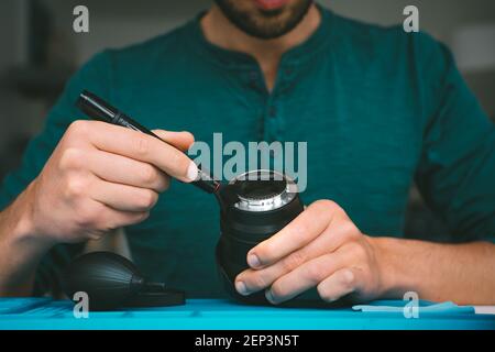 Man cleaning camera lens with brush or lens pen cleaner. Photography equipment care Stock Photo