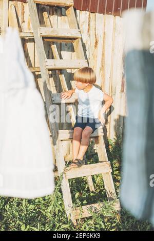 Cute blonde climbs up the ladder countryside cottagecor on summer Stock Photo