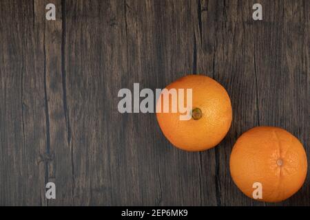 Two whole healthy orange fruits on wooden table Stock Photo