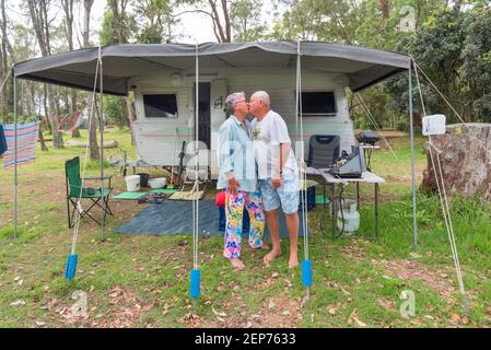Grey nomads, Vicki and Gary (Middo) Middleton in front of their caravan and awning at a camping area in Bendalong, New South Wales, Australia Stock Photo