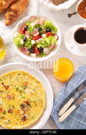 Broad assortment of food including omelette, croissants, salad, bread, coffee and orange juice served on a table Stock Photo