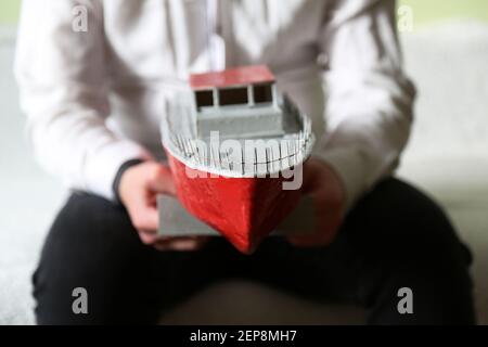 The guy is holding a makeshift ship. A yacht made by a boy. A toy ship.  Stock Photo