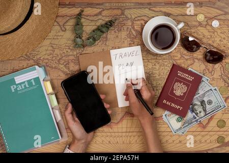 Huzhou, China, 27 February 2021: Planning vacation, travel plan, trip vacation using world map with accessories. Top view, flat lay. Russian