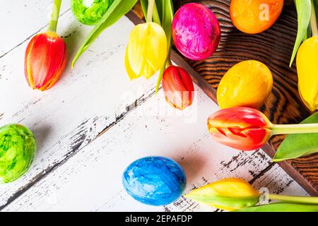 Easter set: painted eggs and fresh tulips flower on wooden table. Stock Photo