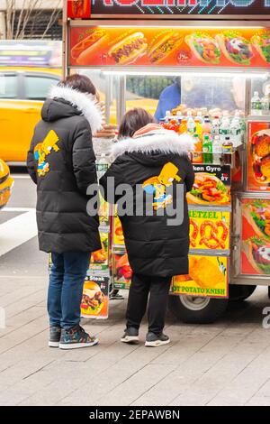 asian couple in identical Simpsons coats at food stands outside of New York The Metropolitan Museum of Art in NYC Stock Photo