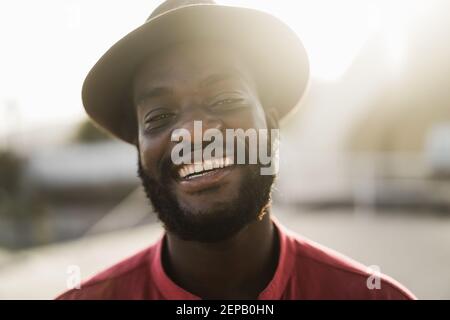 Young african man smiling on camera outdoors with city in background - Main focus on nose Stock Photo