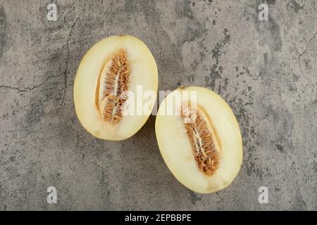 Two halves of yellow sweet melon on marble surface Stock Photo