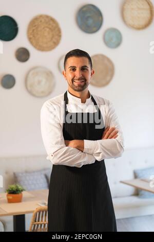 Young chef posing in uniform and kitchen gown in restaurant Stock Photo