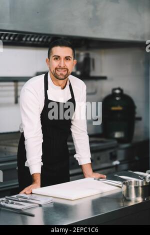 Portrait of a Professional chef posing and wearing uniform and gown in kitchen Stock Photo