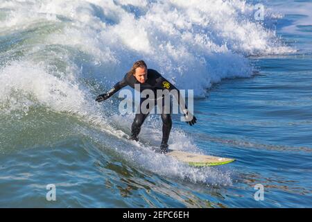 Bournemouth, Dorset UK. 27th Febuary 2021. UK weather: lovely warm sunny day with blue skies and unbroken sunshine at Bournemouth beaches as people head to the seaside for their daily exercise during Lockdown 3.  Surfers enjoy surfing in the sunshine. Credit: Carolyn Jenkins/Alamy Live News Stock Photo