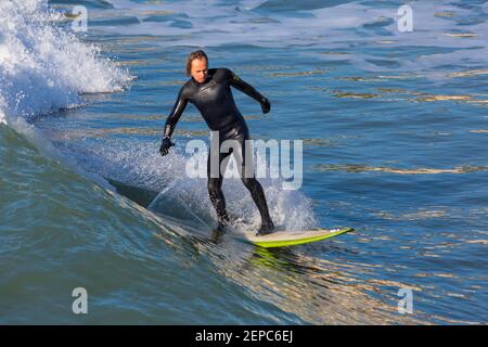 Bournemouth, Dorset UK. 27th Febuary 2021. UK weather: lovely warm sunny day with blue skies and unbroken sunshine at Bournemouth beaches as people head to the seaside for their daily exercise during Lockdown 3.  Surfers enjoy surfing in the sunshine. Credit: Carolyn Jenkins/Alamy Live News Stock Photo