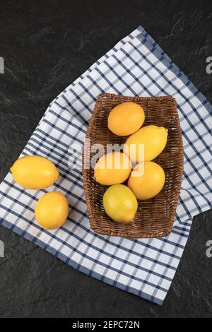 Wooden wicker basket of whole lemons on black surface Stock Photo