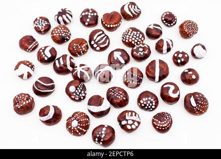 Wild Chestnuts decorated with white paint and in minimal focus against a white background. DIY autumn idea for children. Stock Photo