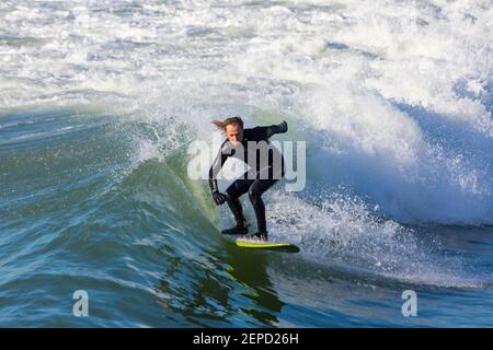 Bournemouth, Dorset UK. 27th Febuary 2021. UK weather: lovely warm sunny day with blue skies and unbroken sunshine at Bournemouth beaches as people head to the seaside for their daily exercise during Lockdown 3.  Surfers enjoy surfing in the sunshine. Credit: Carolyn Jenkins/Alamy Live News Stock Photo