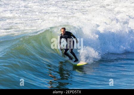 Bournemouth, Dorset UK. 27th Febuary 2021. UK weather: lovely warm sunny day with blue skies and unbroken sunshine at Bournemouth beaches as people head to the seaside for their daily exercise during Lockdown 3.  Surfers enjoy surfing in the sunshine. Credit: Carolyn Jenkins/Alamy Live News Stock Photo