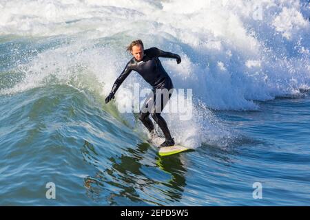 Bournemouth, Dorset UK. 27th Febuary 2021. UK weather: lovely warm sunny day with blue skies and unbroken sunshine at Bournemouth beaches as people head to the seaside for their daily exercise during Lockdown 3.  Surfers enjoy surfing in the sunshine. Credit: Carolyn Jenkins/Alamy Live News Stock Photo