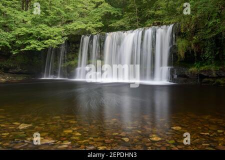 Sgwd Ddwli Uchaf surrounded by vibrant green foliage on a summer afternoon in the Brecon Beacons, Wales. Stock Photo