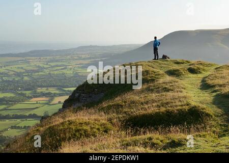 A male hiker surveying the landscape from Mynydd Troed in the Brecon Beacons, Wales. Stock Photo