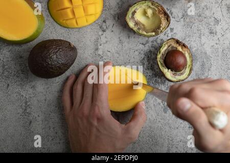 Male hands cutting mango into the cubes on marble surface Stock Photo